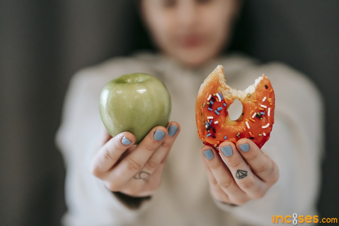 Woman showing apple and bitten doughnut